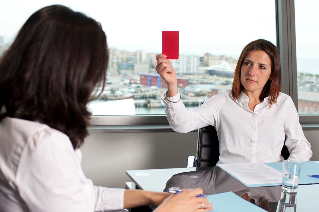 Applicant holding red card during job interview.